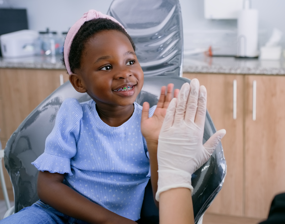 Michael-Riordan-DMD-little-girl-with-colored-braces-in-chair