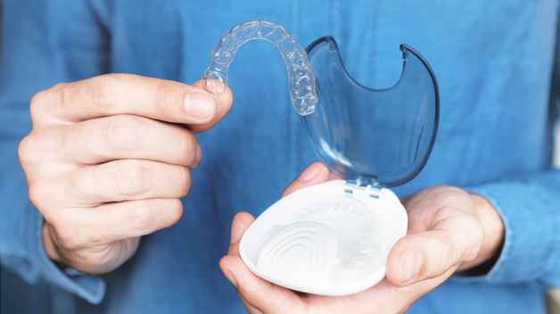 Michael-Riordan-Orthodontics-man-holding-aligner-braces